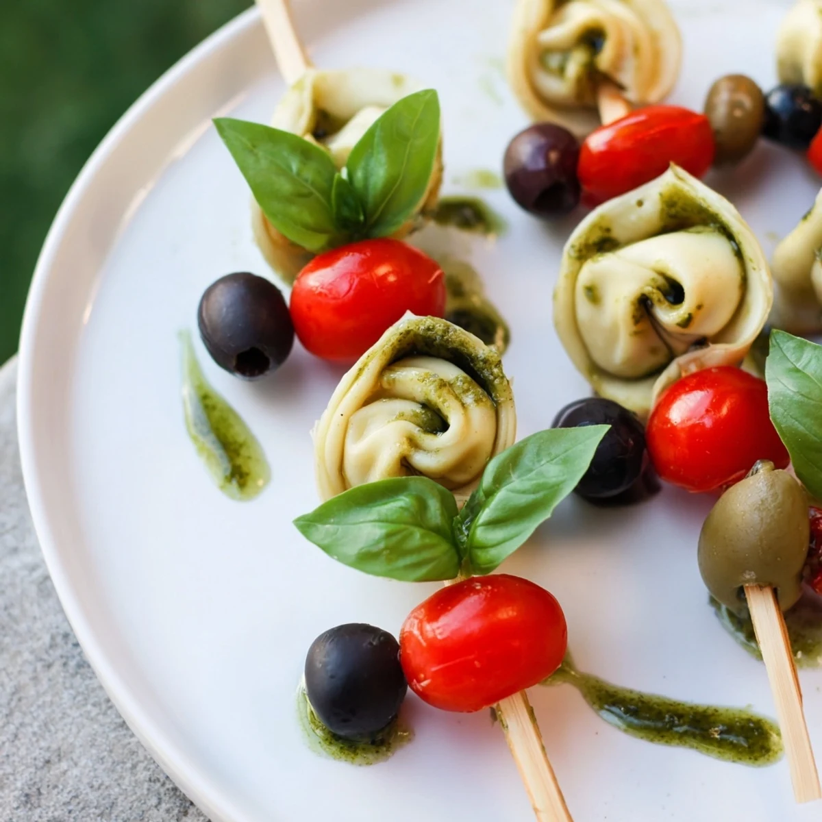 Enjoy these easy Italian-inspired appetizer skewers featuring flavorful tortellini, balanced by olives and fresh pesto.