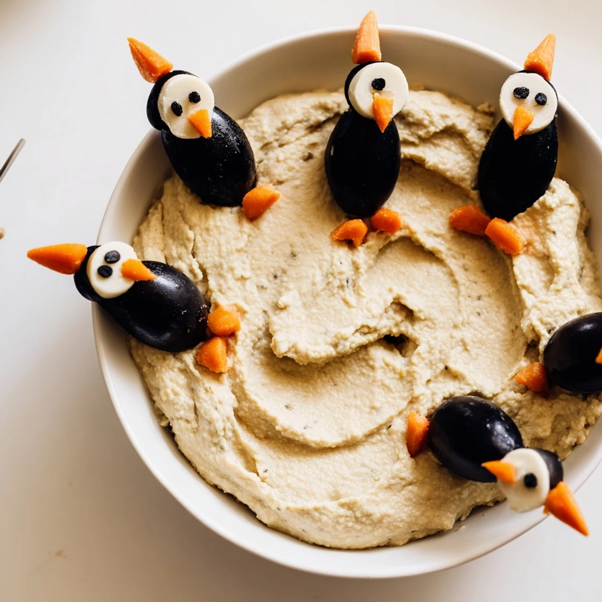 A festive Winter Dip: White bean dip adorned with adorable olive penguin decorations ready to serve.