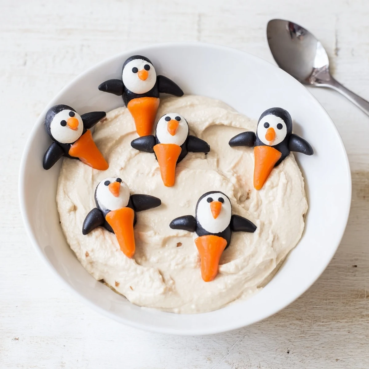 Creamy white bean Winter Dip, a Mediterranean-inspired appetizer, topped with cute olive penguins and carrot feet.
