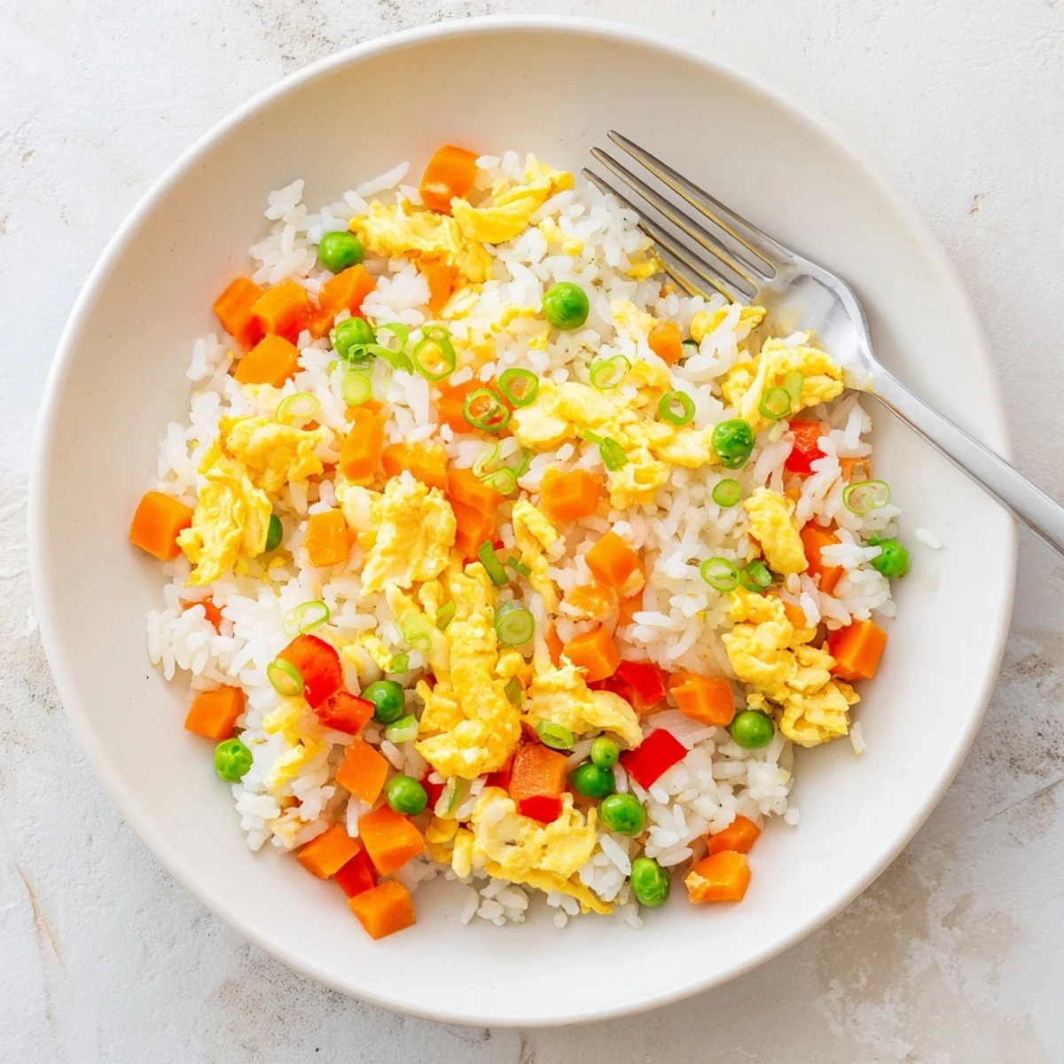 Fluffy eggs and colorful vegetables mixed into a steaming hot pan of classic egg fried rice, ready to serve.