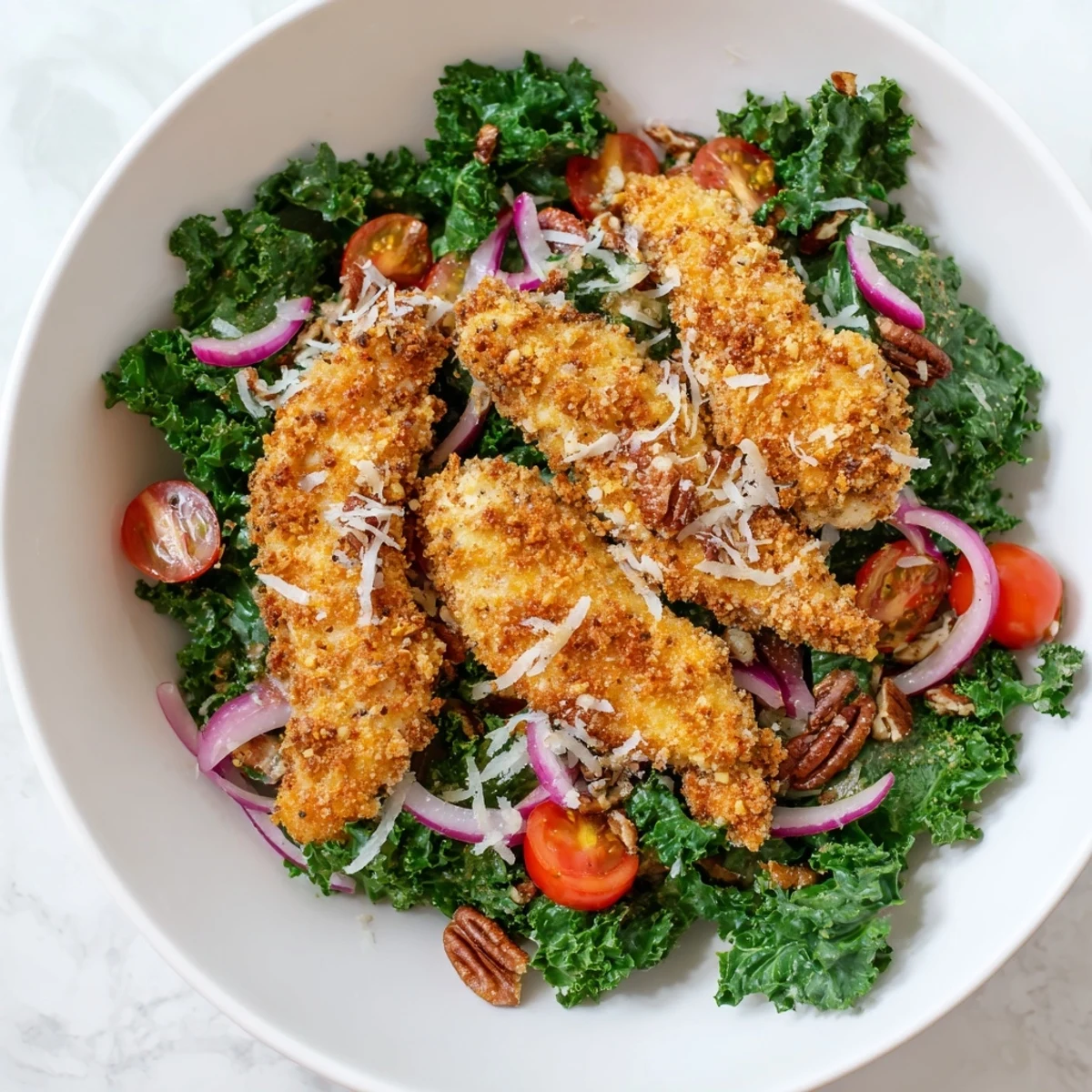 A hearty lunch salad featuring crispy panko-crusted chicken, massaged kale, toasted pecans, and a vibrant maple-Dijon vinaigrette for a satisfying meal.