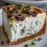 Savory Kalamata cheesecake appetizer slice being lifted, revealing creamy filling and crunchy herbed breadcrumb crust.