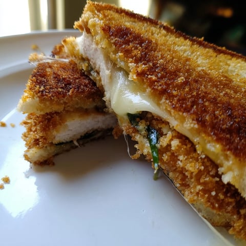 Golden, crispy Parmesan Chicken Thighs Grilled Cheese, oozing melted cheese between toasted sourdough slices, ready to serve.