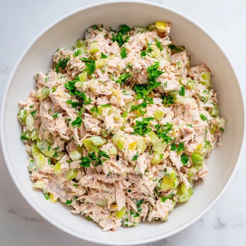 A close-up of the Spicy Zesty Tuna Salad in a rustic bowl, garnished with fresh parsley and a lemon wedge.