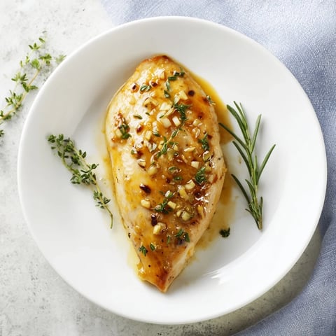 Golden-brown chicken breasts glisten in a skillet, smothered in a glossy honey Dijon sauce with fresh thyme and rosemary.