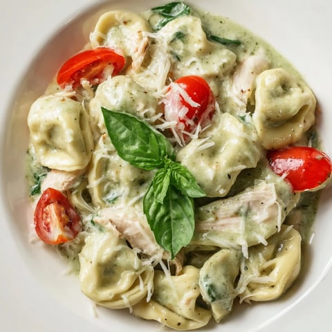 Golden, creamy pesto sauce coats cheese tortellini and rotisserie chicken in a bubbling skillet.