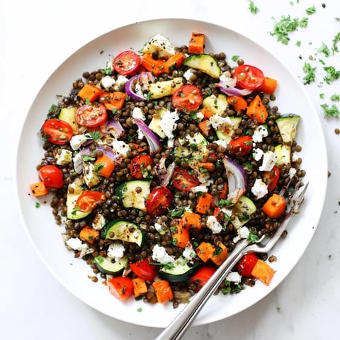 A close-up of Black Lentil Salad with Roasted Vegetables, featuring tender beluga lentils, colorful caramelized vegetables, and fresh parsley with a lemony sheen.  