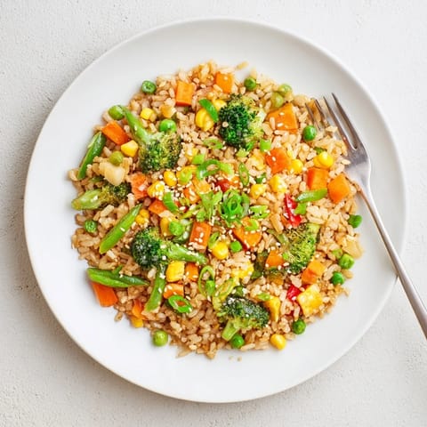 Brightly colored Vegetable Fried Rice with broccoli, carrots, and peas served hot in a white bowl, garnished with green onions.