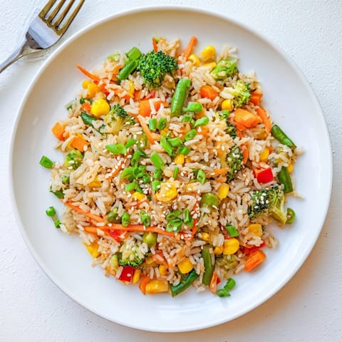 Sizzling Vegetable Fried Rice being tossed in a wok, featuring crisp veggies and steam rising for an aromatic meal.