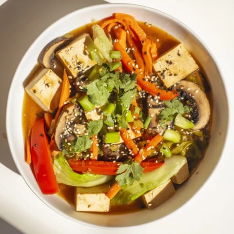 A steaming bowl of Tofu and Vegetable Soup, featuring silken tofu cubes, julienned carrots, and vibrant bok choy in a light ginger broth.