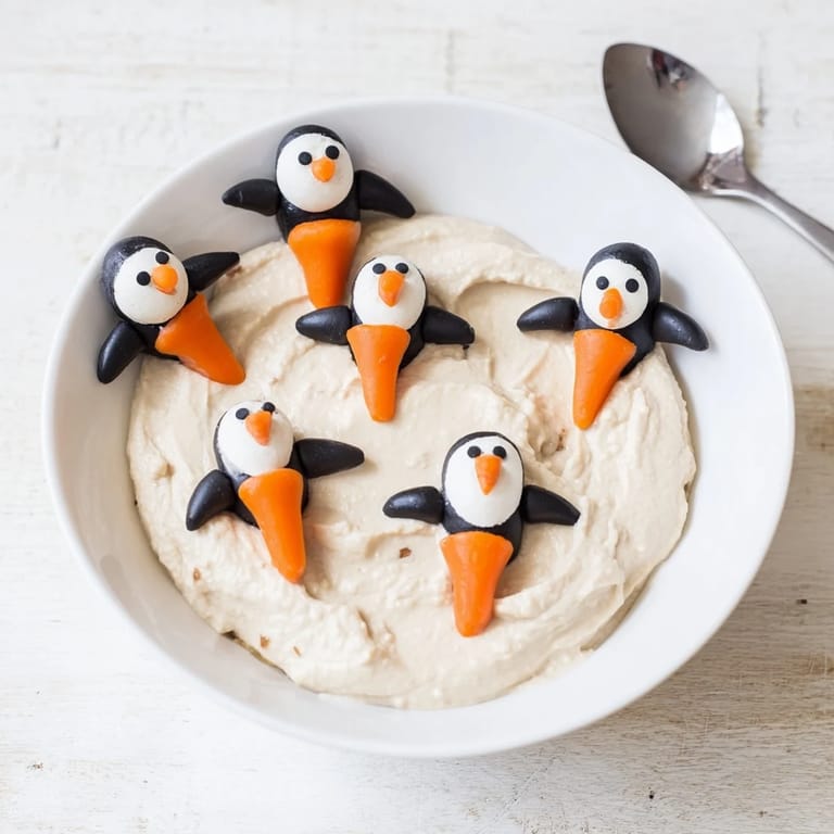 Creamy white bean Winter Dip, a Mediterranean-inspired appetizer, topped with cute olive penguins and carrot feet.