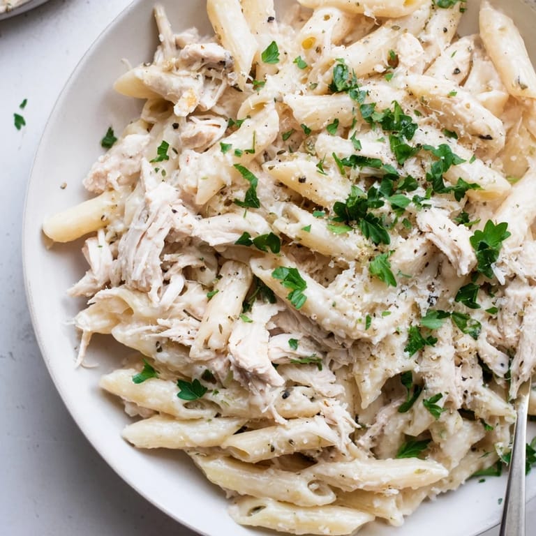 A close-up view of creamy Tinis Chicken Pasta with tender chicken, ready for a comforting meal.