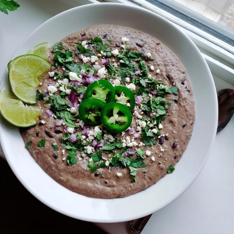 Close-up of creamy Spicy Black Bean Dip, seasoned with jalapeño, garnished with lime.