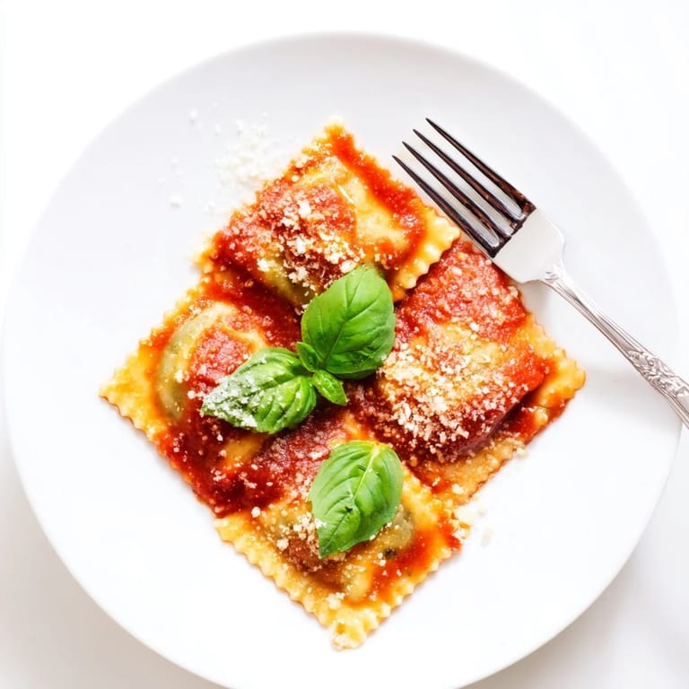 Close-up of golden Spinach Ricotta Ravioli, revealing creamy filling in rich tomato sauce on a rustic plate.