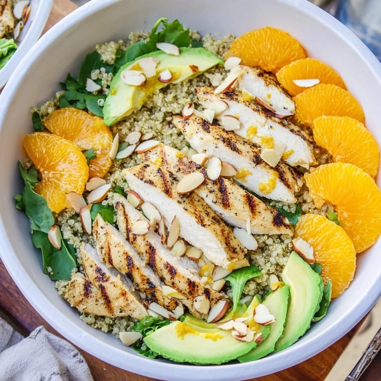 Freshly grilled herb chicken rests atop a bed of mixed greens and quinoa in this bright salad bowl.