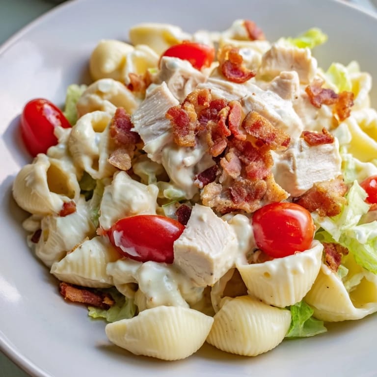 Bright and colorful BLT Chicken Pasta Salad garnished with diced bacon and juicy tomatoes, ready for a summer potluck.