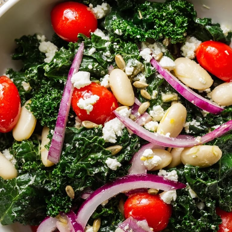 In the background, a jar of lemon-garlic dressing is ready to pour over the White Bean and Kale Salad, featuring fresh kale, red onion slices, and white beans.