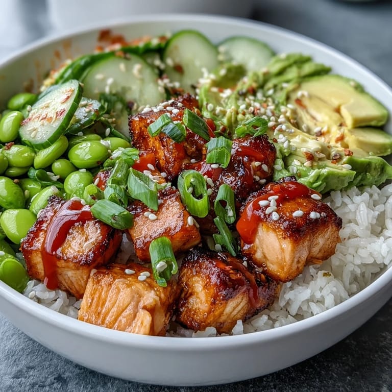 Artfully arranged baked salmon and avocado pieces sit on warm jasmine rice in a Salmon Rice Bowl, sprinkled with sesame seeds.