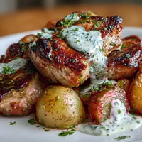 Golden-seared Crockpot Ranch Pork Chops in creamy gravy with tender potatoes and carrots, served on a plate.